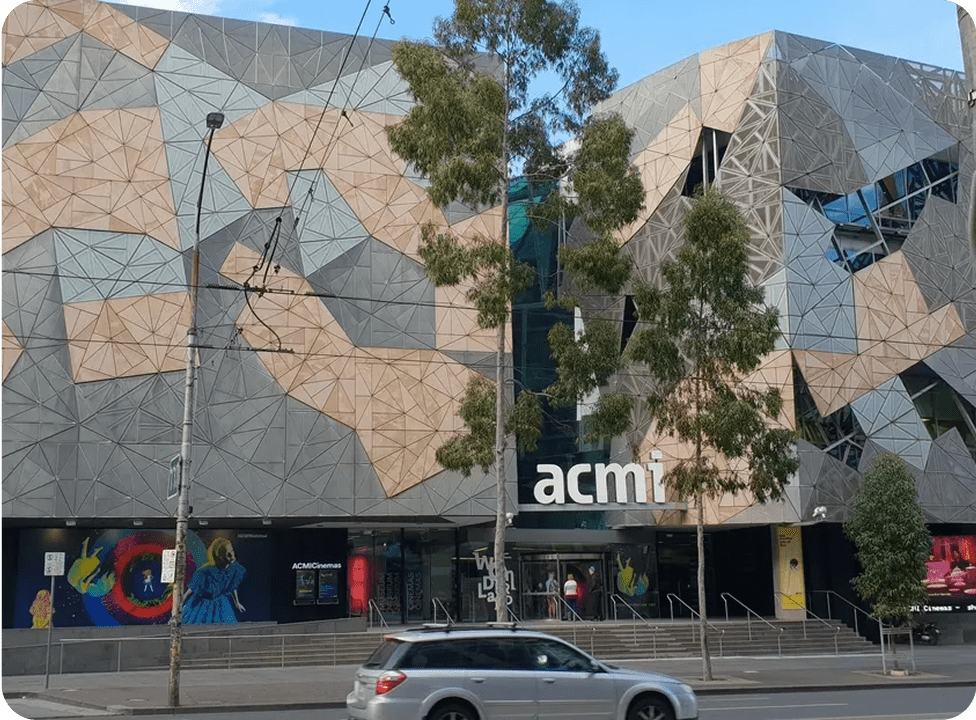 Geometric building facade with trees and car.