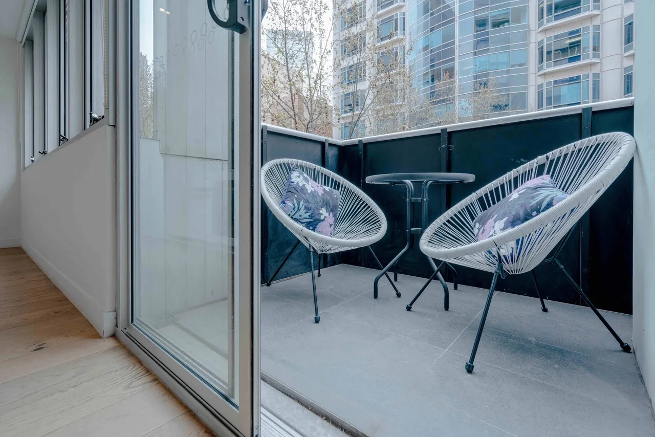 Balcony with chairs and small table outside.