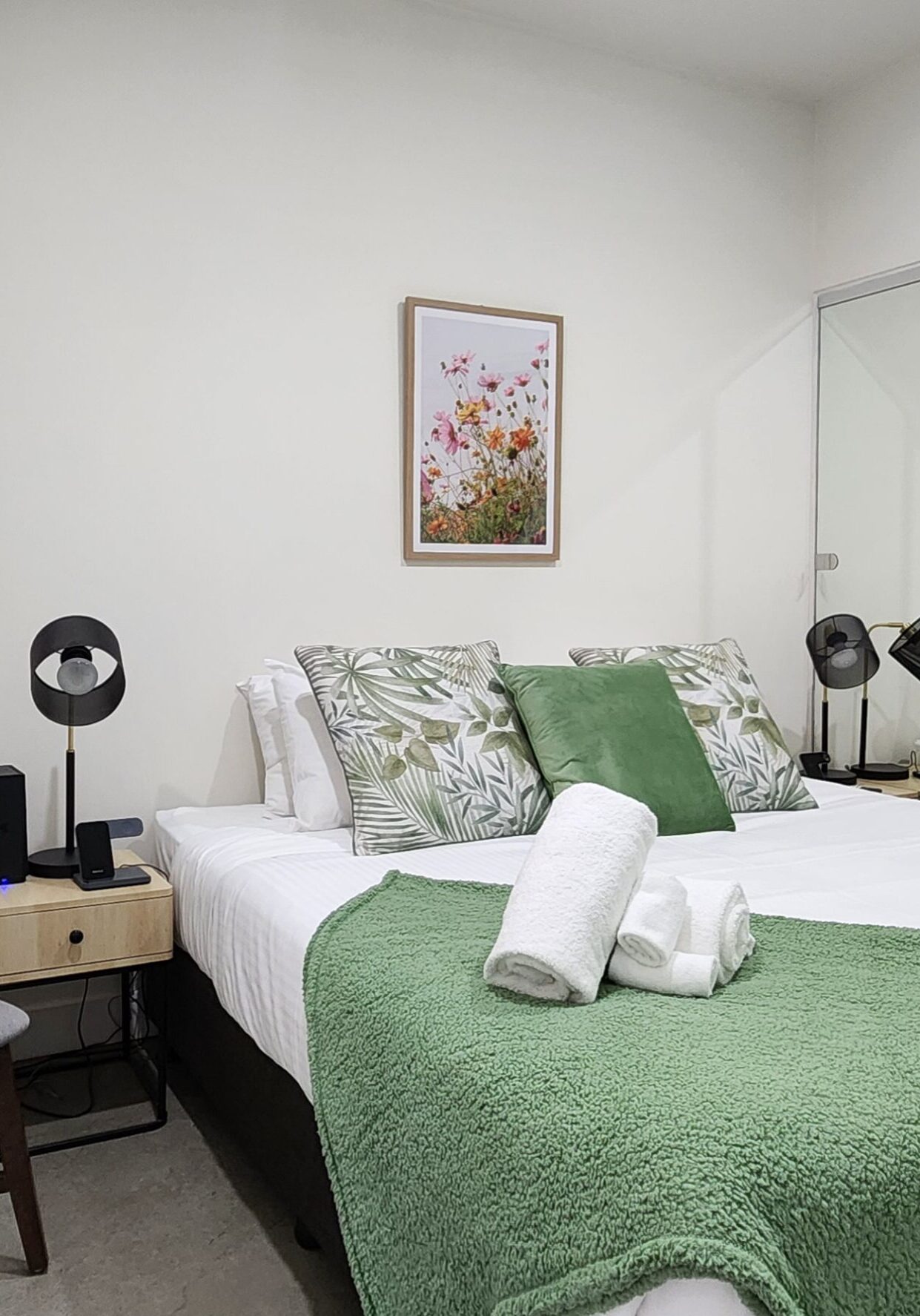 Cozy bedroom with green and white bedding and modern decor.